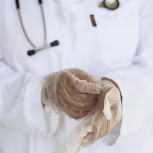 Lekarz akredytowanego szpitala nakładający przezroczyste jednorazowe rękawiczki.