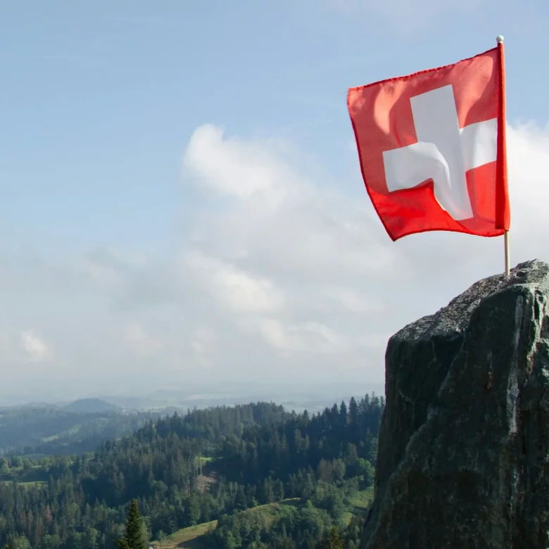Flaga szwajcarska na tle gór.