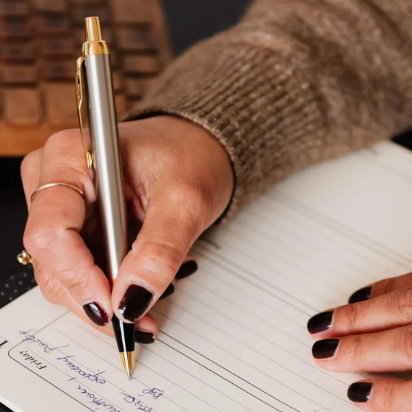 Zbliżenie na dłoń kobiety podpisującej dokumentację związaną z Fundacją Rodzinną.