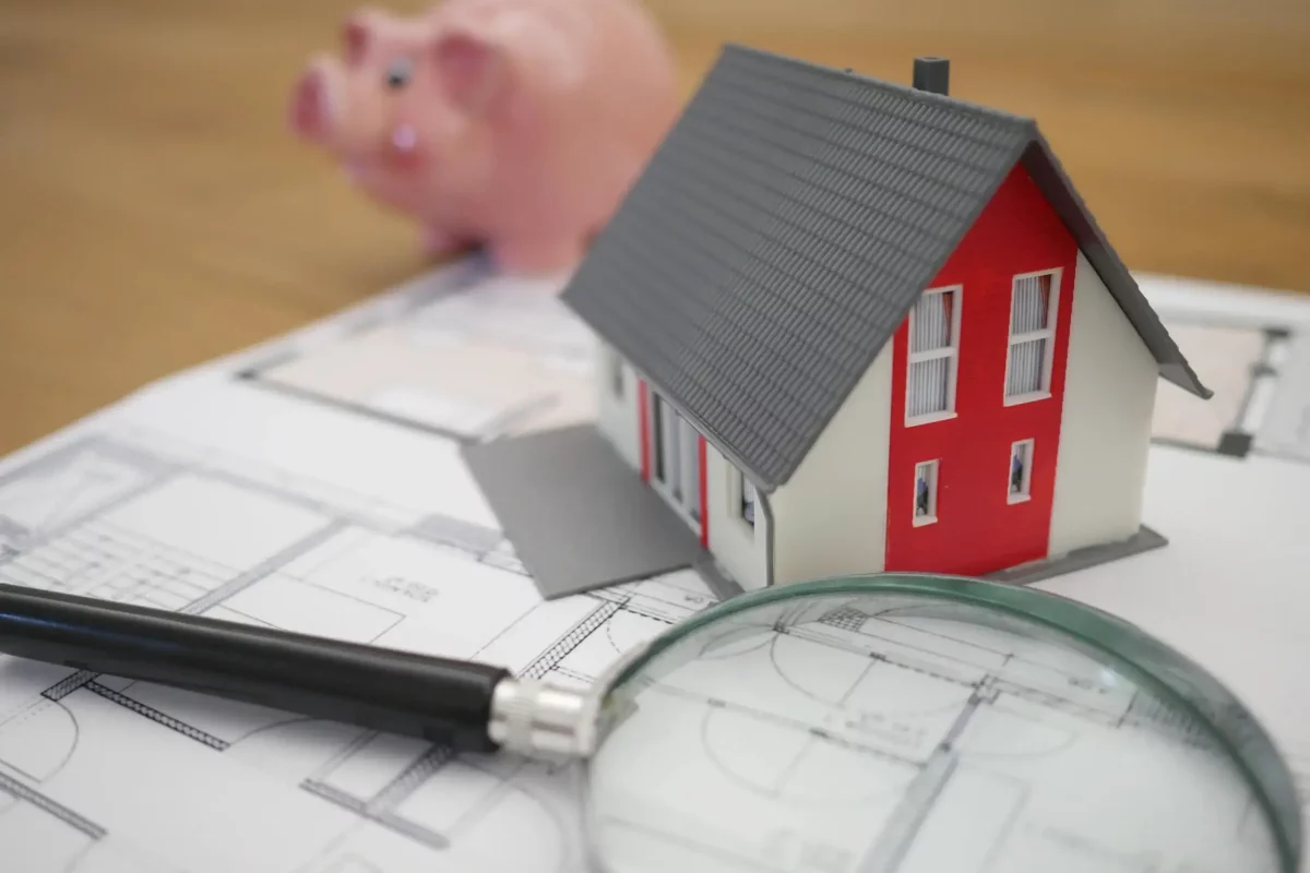 Plany domu, makieta domu i świnka skarbonka z oszczędnościami osoby chcącej wziąć kredyt hipoteczny