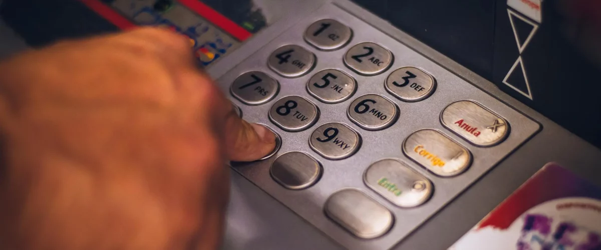 Dłoń człowieka wypłacającego pieniądze z bankomatu.