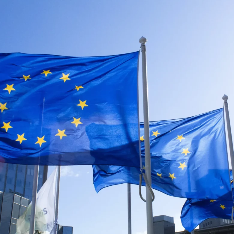Flagi Unii Europejskiej na tle budynku Trybunału Sprawiedliwości Unii Europejskiej.